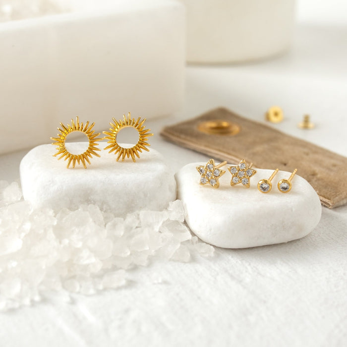 Flower Stud Gift Set featuring gold sunburst earrings and crystal star studs on white stones.