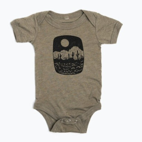 Taupe baby onesie with a black desert landscape inside a rounded rectangle on the chest.