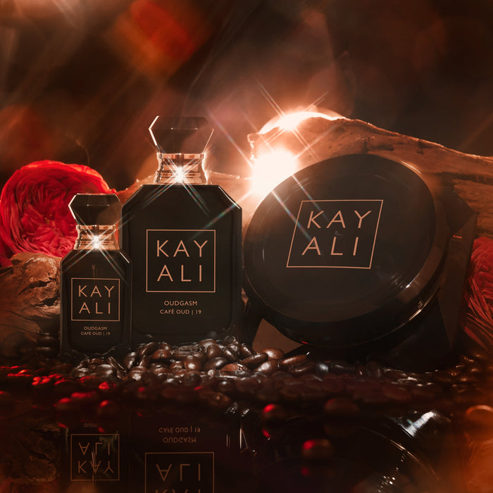 KAYALI perfume bottles and packaging on a dark background with red flowers.