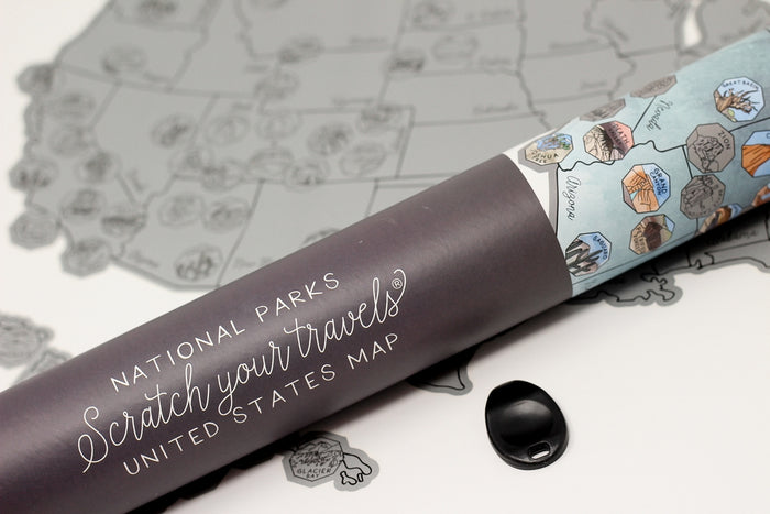 Close-up of the rolled National Parks Scratch-Off map with a purple tube and a black cap on a white surface