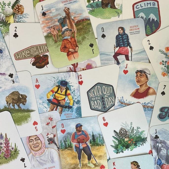 Close up of A Woman's Place is in the Wild playing cards featuring hikers, wildlife, and nature scenes.