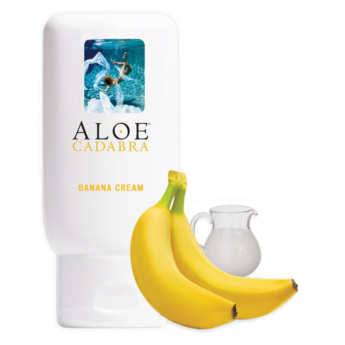 Aloe Cadabra Banana cream organic natural lubricant in a white squeeze bottle. In front of a bottle two bananas and a glass of milk.