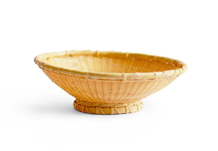 Bamboo woven bowl sitting against white background.