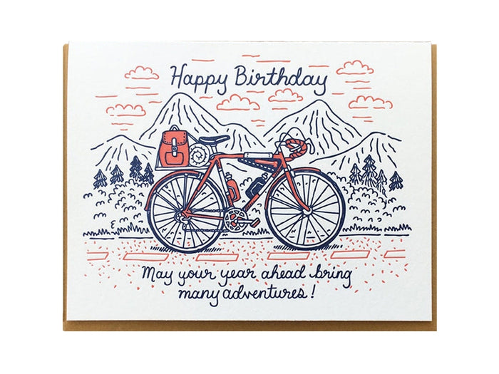 Birthday card with a red bicycle, mountain landscape and clouds, and Happy Birthday message.