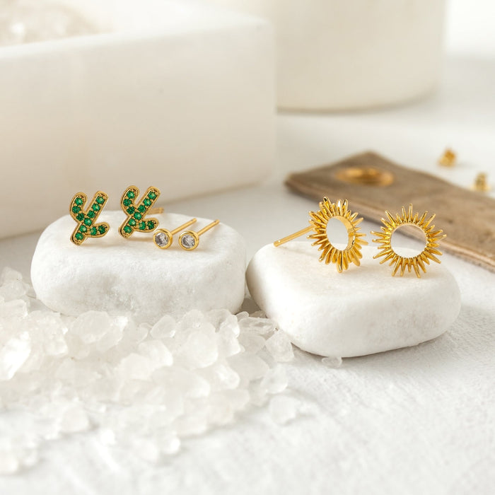 Gold cactus shaped stud earrings with green stones from the Cactus Stud Gift Set, displayed on white stones