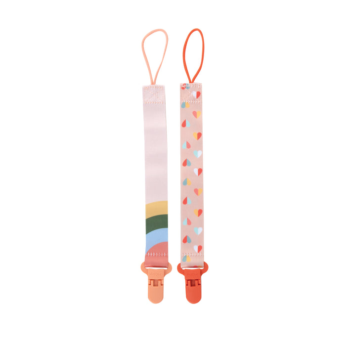 The Cloth Pacifier Clip (2 Pack) features one rainbow and one multicolored hearts design. Each has a loop at the top and a pink clip at the bottom to keep your baby's pacifier secure and add a stylish touch.