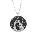 Round silver pendant necklace featuring a Delicate Arch silhouette against a starry night background.