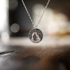 Close-up of the Delicate Arch round pendant on a silver chain with a soft, out-of-focus background.