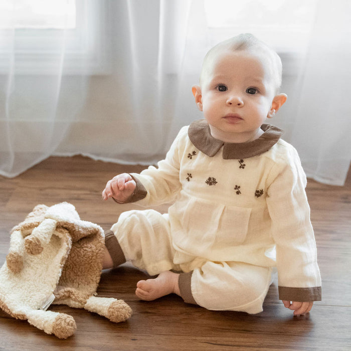 Baby in Organic Embroidered Crinkle Muslin Baby Jumpsuit playing with Viverano lovey toy