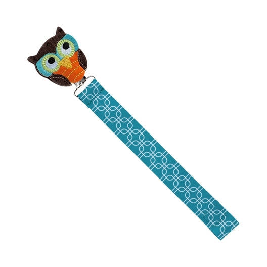 The Nuby Felt Pacifier Clip features a brown and teal embroidered owl head with large eyes and an orange beak, attached to a teal strap with a white geometric pattern and metal clip. It doubles as an adorable pacifinder or bookmark.