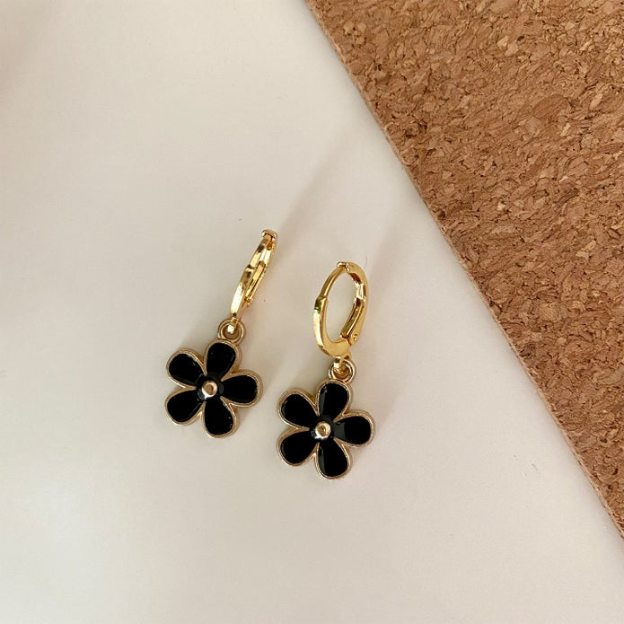 Gold hoop earrings with black enamel five-petal flower charms and a small central gem