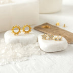 Flower Stud Gift Set featuring gold sunburst earrings and crystal star studs on white stones.