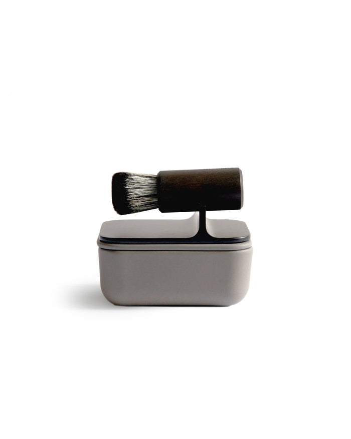 Silhouetted image of hard Jiva face cleansing and shaving series with porcelain bowl and walnut, boar bristle, and goat hair brush by Shaquda against white background.