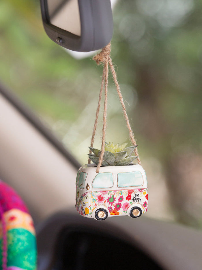 Mini hanging van planter with a succulent and floral pattern, suspended by twine from a car rearview mirror.