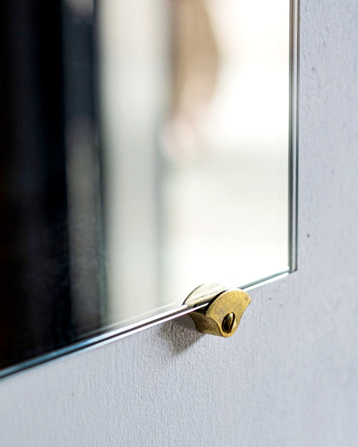 Angled view of one matureware mirror stopper holding a square mirror.