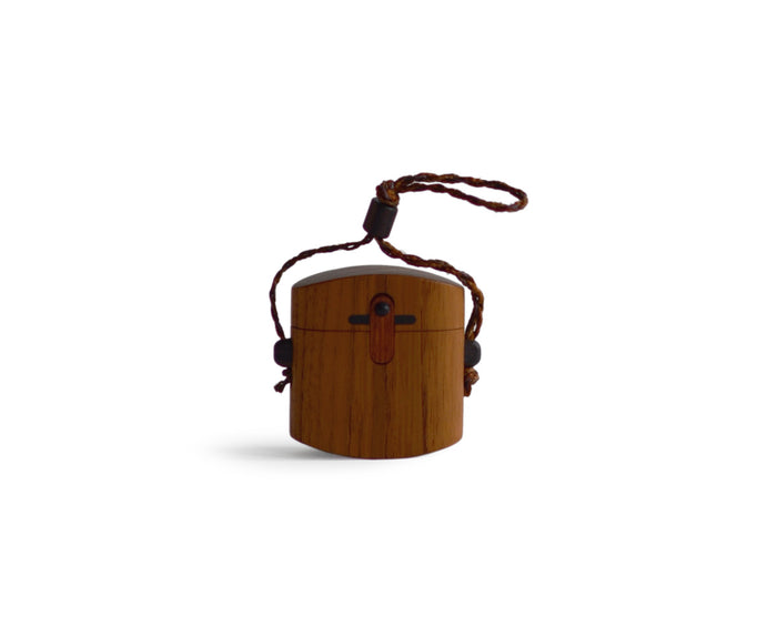 Silhouetted image of walnut pill case with cord by Norio Tanno against white background.