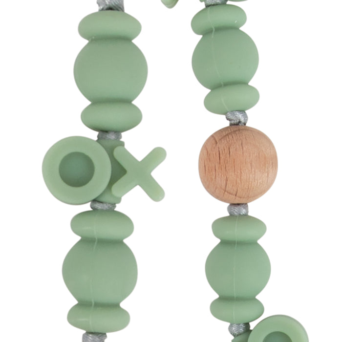 Close-up of a Silicone and Wood Beaded Pacifier Clip featuring light green silicone beads, wooden beads, and letter beads spelling O and X on a gray cord.