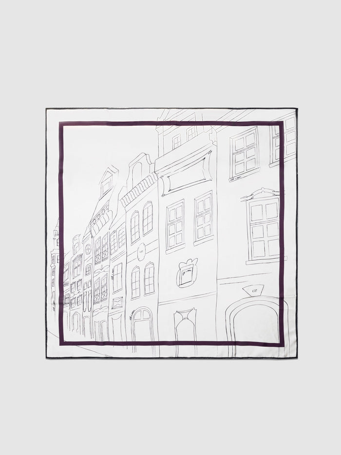 Silk Scarf, Pueblo, Cloth and Paper. Scarf displayed on a neutral background. It features a hand-drawn pattern with buildings and purple accents.