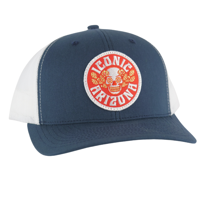 Navy blue curved brim trucker hat with white mesh and round patch showing a skull surrounded by flowers and Iconic Arizona text.
