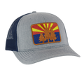 AZ Pines curved trucker hat with light gray front panel, navy mesh back, and a desert sunrise pine patch