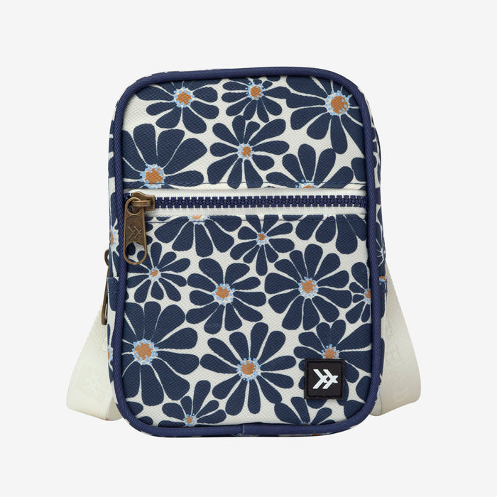 Small crossbody bag with navy floral print and front zipper pocket.