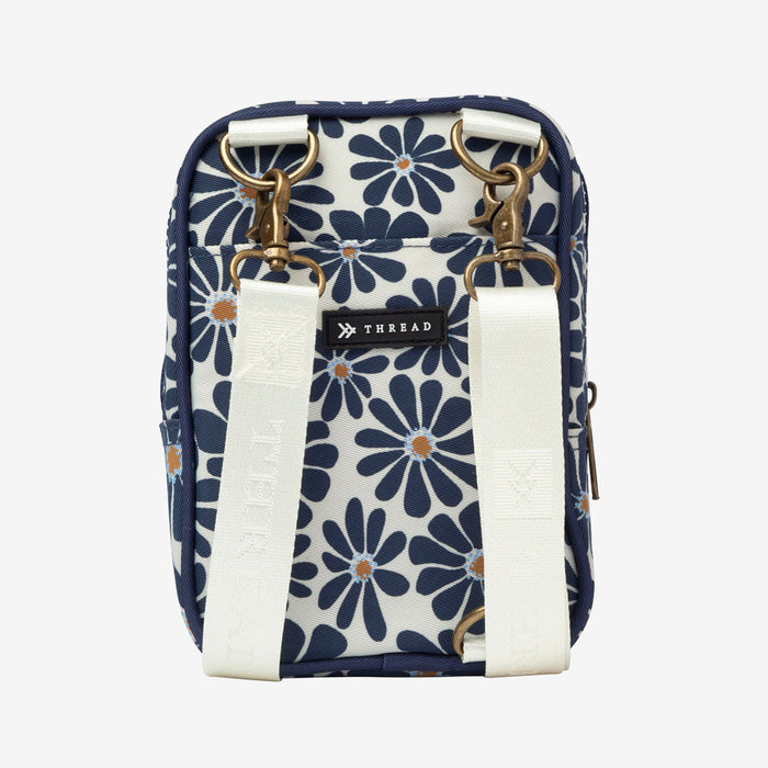 Thread crossbody bag with navy floral print and white adjustable strap and brass hardware.