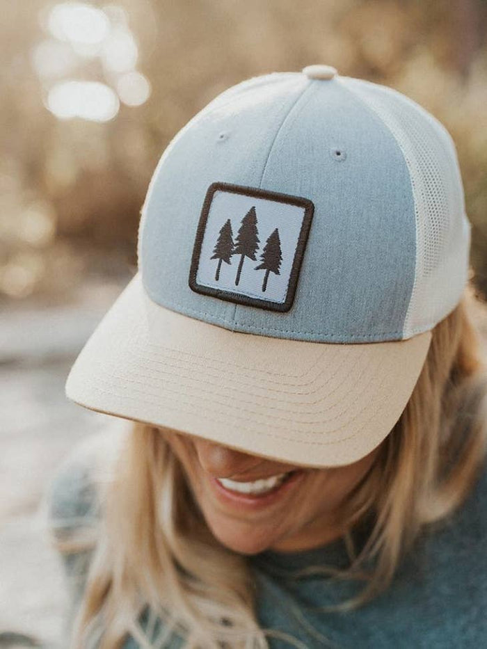 Powder blue front-panel trucker hat with beige brim and a patch of three trees