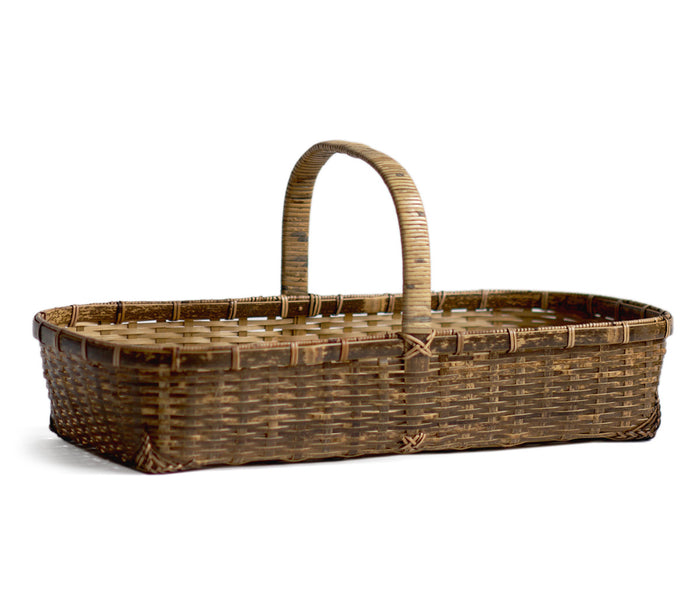 Silhouetted angled image of long toradake bread basket with handle by Kohchosai Kosuga against white background.