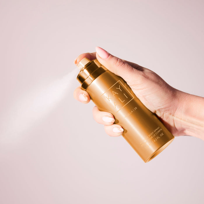 Hand holding a gold bottle with 'KAYALI' branding against a light background
