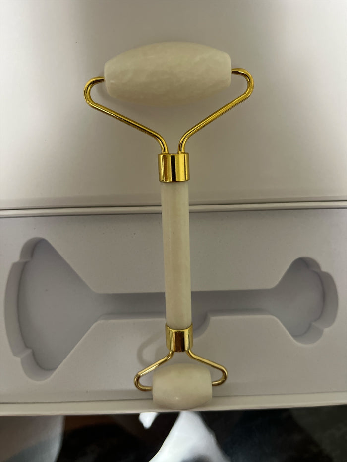 White and gold facial roller on a white background